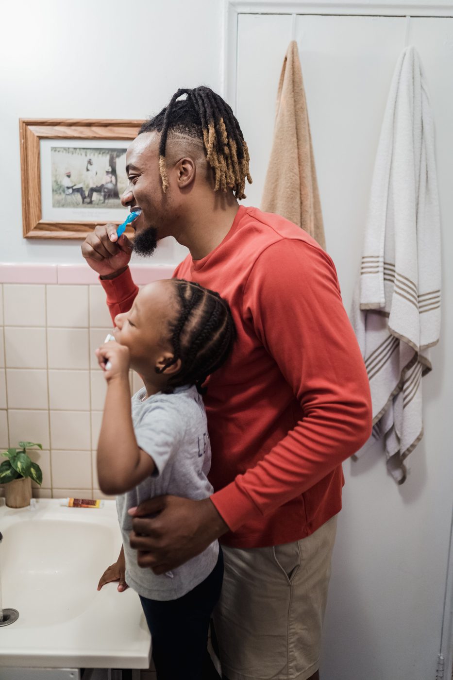 A father and son brushing their teeth together at the bathroom sink